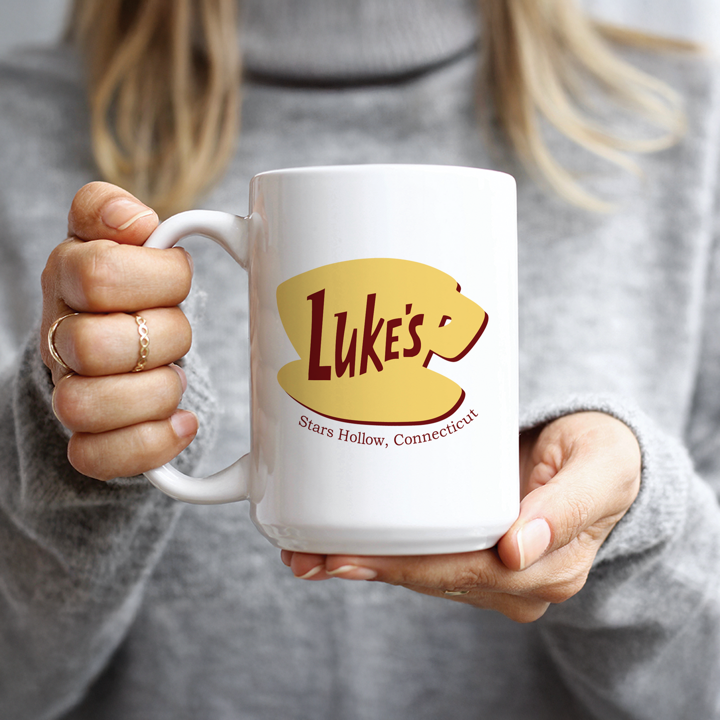 Woman in grey sweater holding cozy Luke's Diner Stars Hollow TV show gift mug