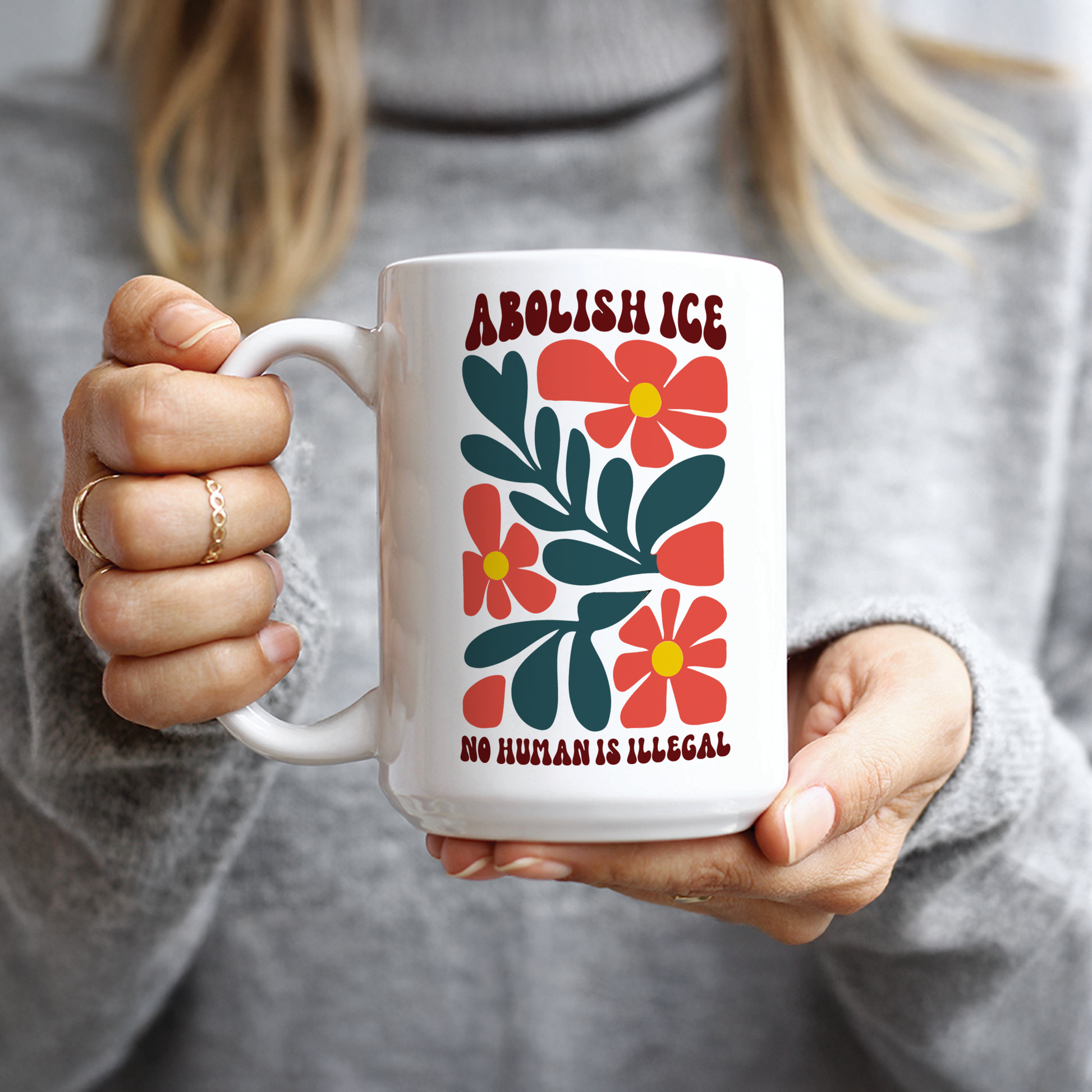 Woman in grey sweater holding retro social justice No human is illegal gift mug