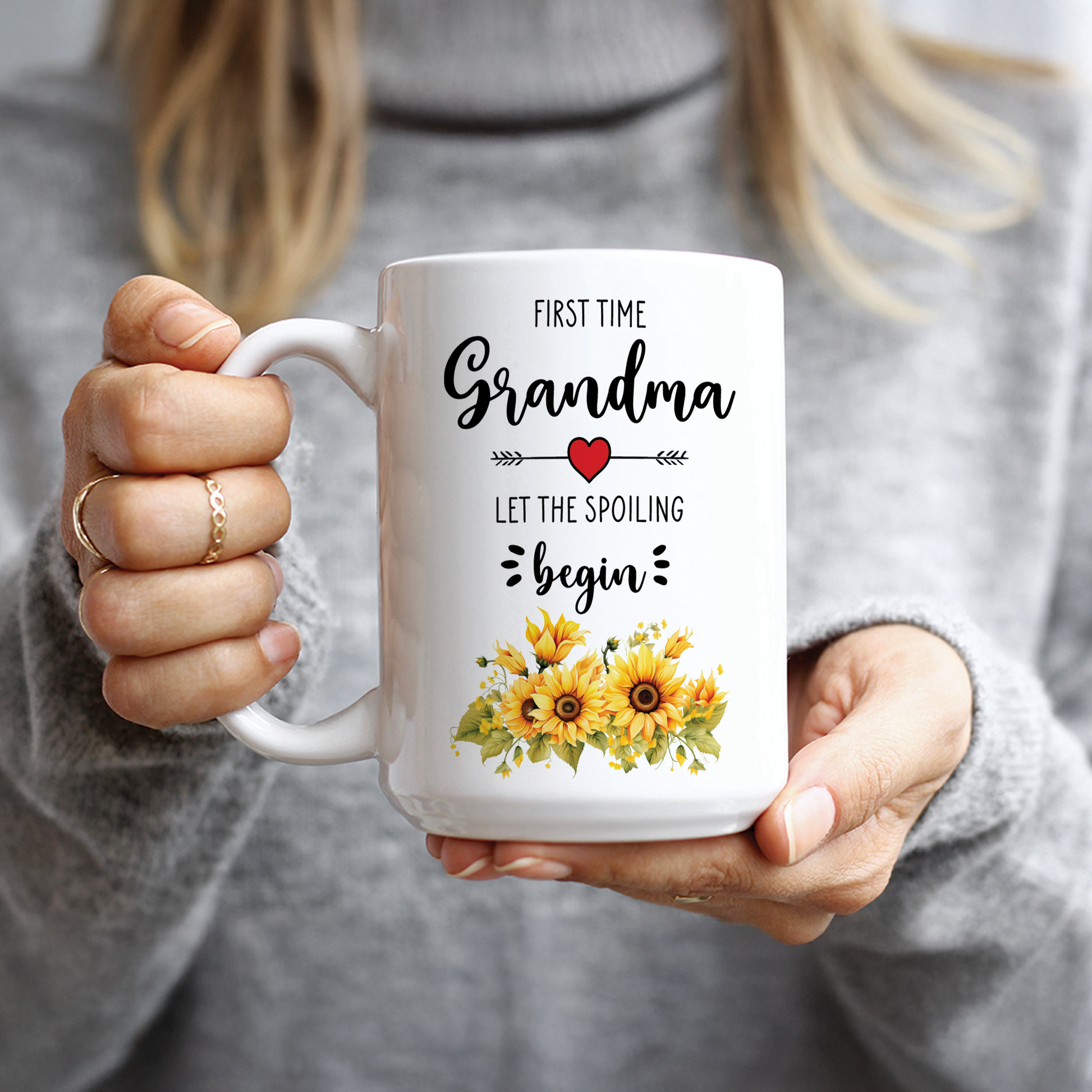 Woman in grey sweater holding sweet First Time Grandma pregnancy announcement gift mug