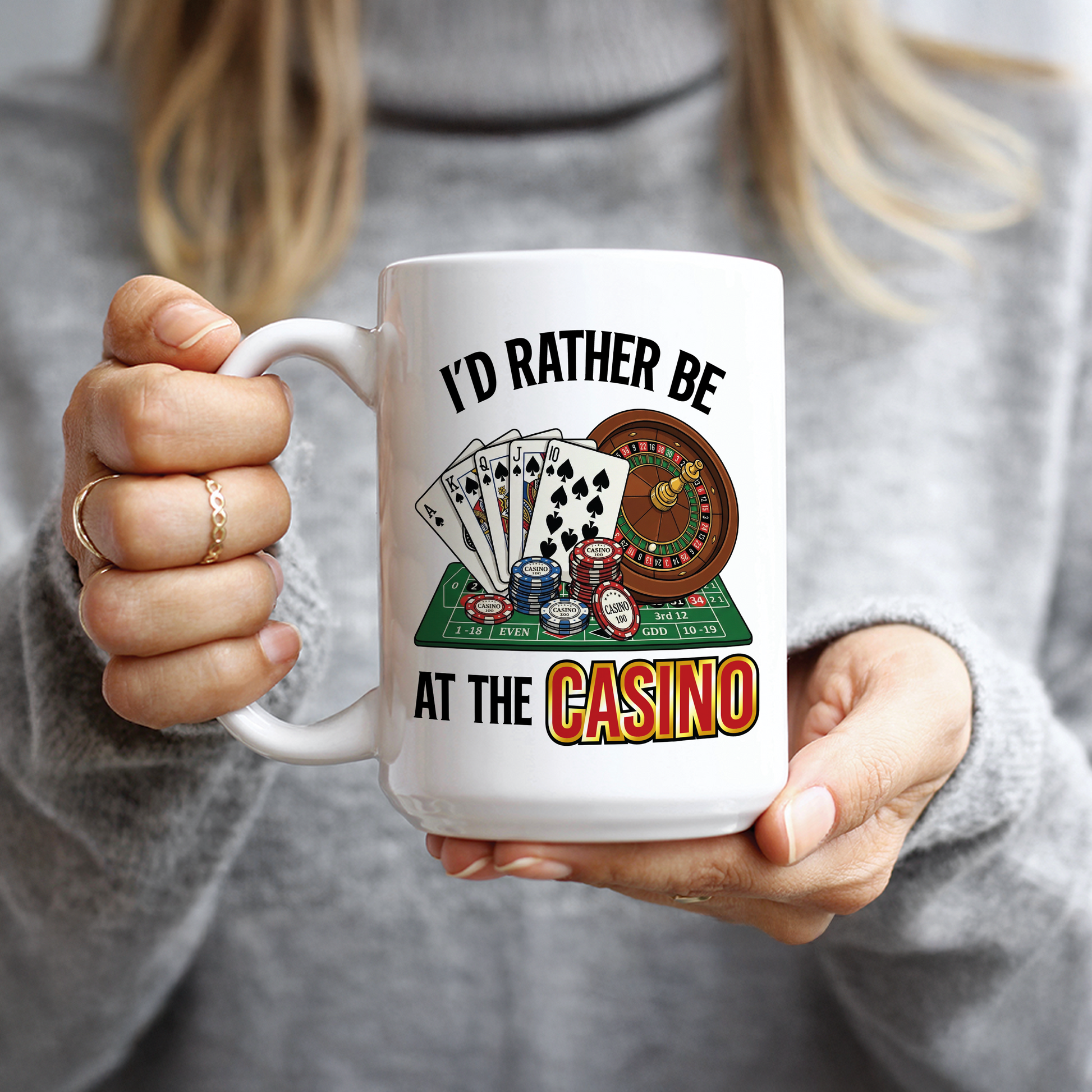 Hand holding white mug with I'd Rather Be At The Casino design