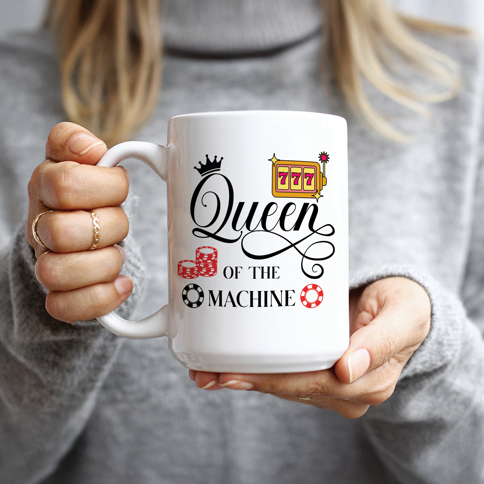 Hand holding white mug with Queen of the Machine casino design